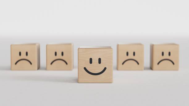 istock Smile face print screen on wooden cube block among sadness face for customer service evaluation and emotion mindset concept.3D rendering on black background. 2186444435