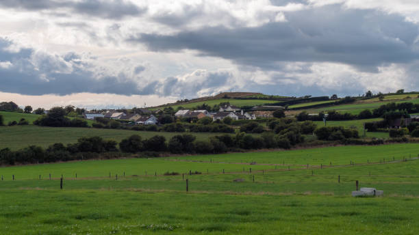 istock A village among fields and trees under a cloudy evening sky, County Cork. Rustic Irish landscape in summer, European village. Green grass field under cloudy sky 2186445795