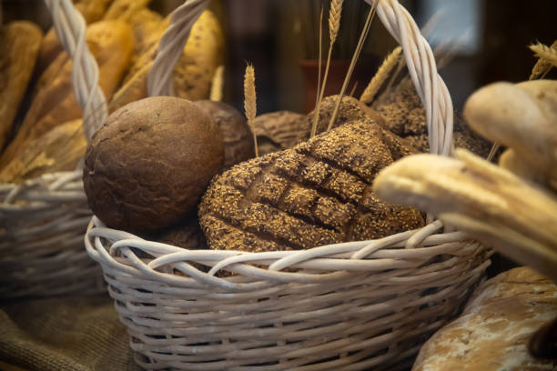 Close-up view of various fresh baked loafs of bread lying on wooden shelf in bakery or supermarket. Soft focus. Copy space. Food business theme.