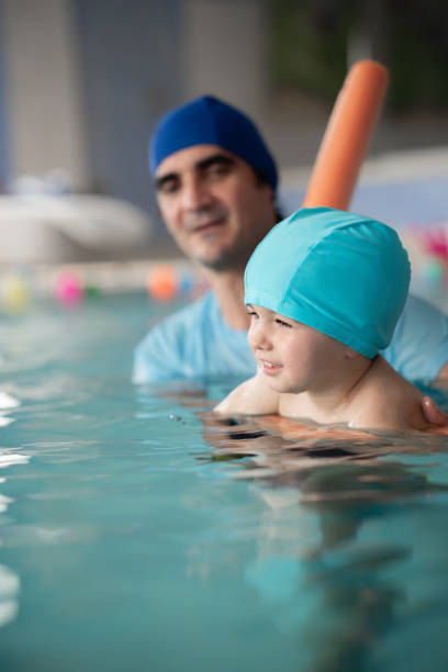 istock Instructor teaching a baby to swim in indoor pool 2186447777
