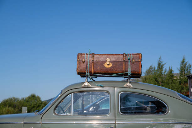 Old suitcase on the roof of a car instead of a modern roof box.