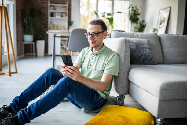 istock Casual man using smartphone seated on cozy floor. 2186455303