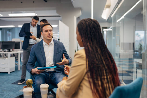 istock Handsome business man holding file folder with documents in hands while sitting in lounge space on coffee break with his colleague 2186456570