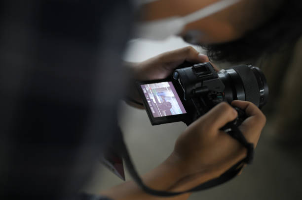Close up of a man holding a modern photo camera while looking at the screen