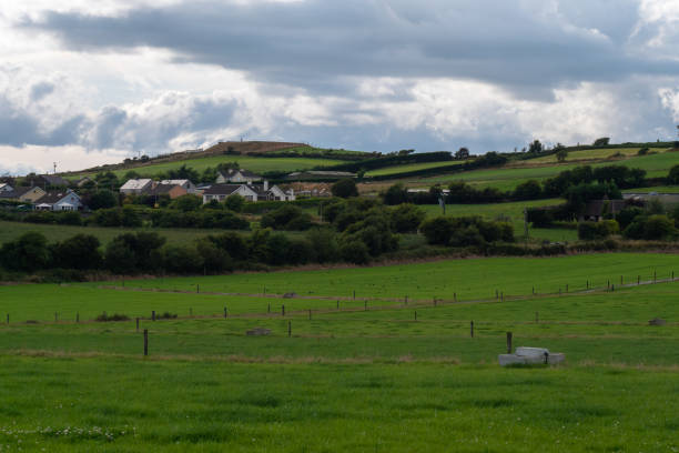 istock A small village among fields and trees under a cloudy evening sky, County Cork. Rustic Irish landscape in summer, European village. Green grass field under cloudy sky 2186457570