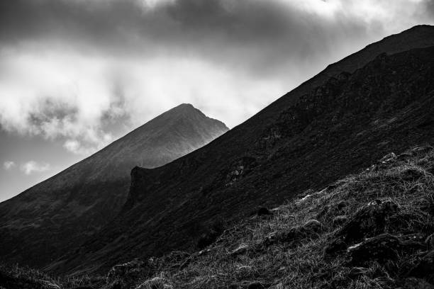 istock Dramatic black and white mountain landscape showcasing rugged peaks and cloudy skies in a moody atmosphere during daylight. 2186458143