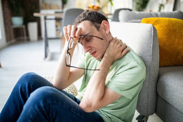 istock Man rubbing his neck, glasses in hand, appearing tense. 2186458197