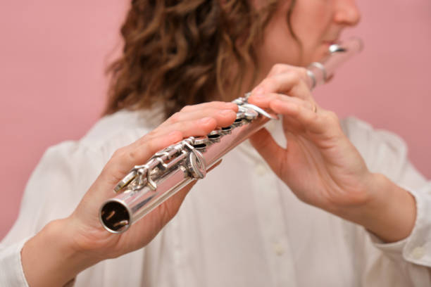 istock Hands playing a silver flute in a close-up view. Studio shot on a soft pink background. Wind instrument performance. Concept of music, art, and creativity. 2186462688