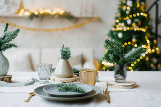istock Decorated New Year's table in light turquoise colors. Vases with spruce branches on the background of Christmas lights 2186463730