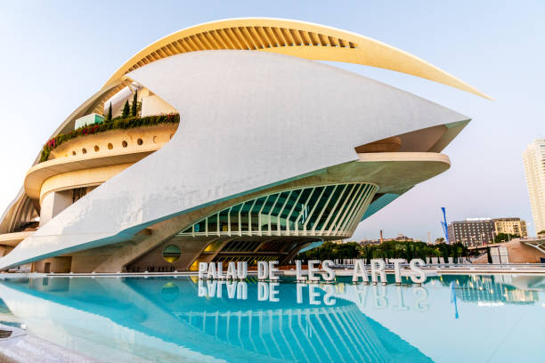 Valencia, Spain - Tuesday, 19th of November 2024: The photo showcases the iconic Palau de les Arts Reina Sofia, a stunning opera house and performing arts center located in the City of Arts and Sciences complex in Valencia, Spain. Designed by renowned architect Santiago Calatrava, the building is a masterpiece of contemporary architecture, featuring futuristic curves, a striking white exterior, and a reflecting pool that enhances its grandeur. The structure’s innovative design and cultural significance make it a symbol of modern Valencia. This image is perfect for illustrating architecture, cultural landmarks, or travel destinations in Spain.