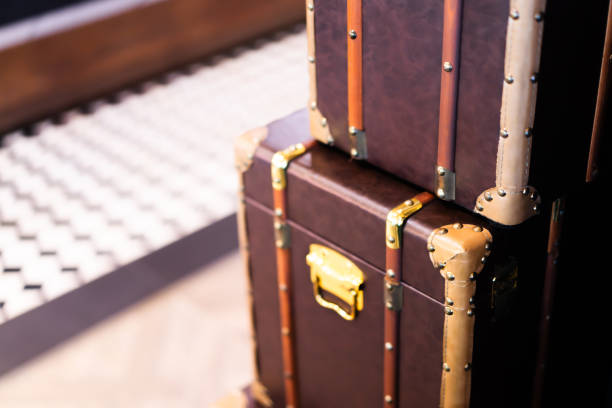 Vintage brown suitcase with textured surface, metal locks, and worn details placed on a rustic wooden luggage shelf inside a retro painted blue wooden interior with a white plank ceiling.