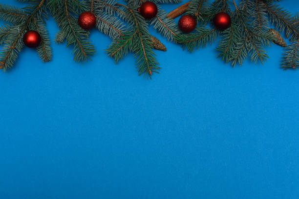 istock Christmas composition with green pine twigs, Christmas tree red balls decorations on blue background with copy space banner. Flat lay. Xmas 2186480505