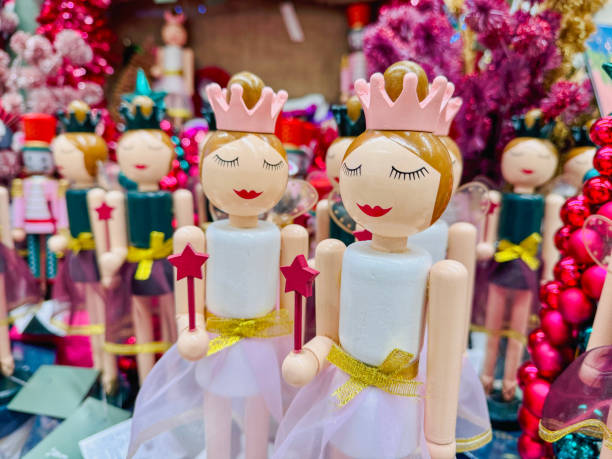 Handcrafted wooden figurines of fairies wearing crowns and holding wands, set against a vibrant holiday-themed background.