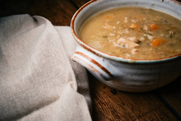 istock Bowl of Chicken, vegetable and grain soup on a rustic wooden table top. 2186484832