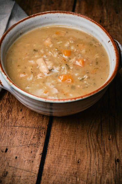 istock Bowl of Chicken, vegetable and grain soup on a rustic wooden table top. 2186484837