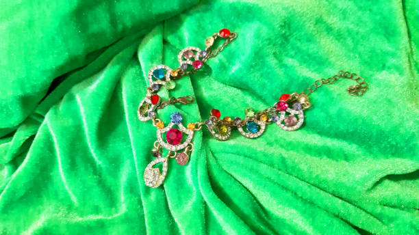 istock Women's gold jewelry with multi-colored stones on a bright green textile. Background design, photography new. Textile, fabric template, photo modern 2186485641