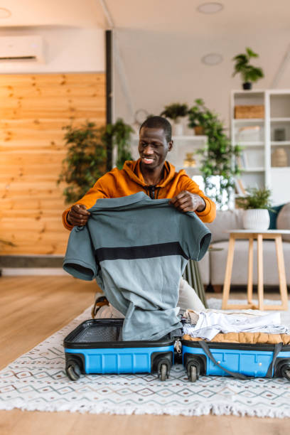 istock Young man packing his staff in suitcase, getting ready for business trip. 2186487995