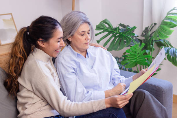 istock Young woman helping senior mother reading documents at home 2186488410