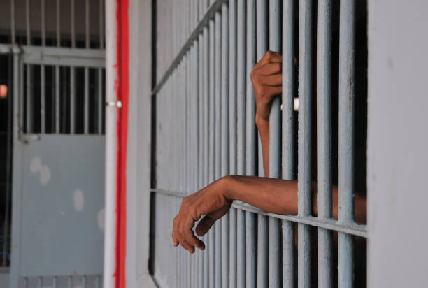 istock close up of prisoner hands in jail background. 2186489045
