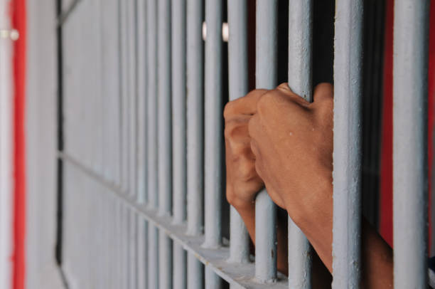 istock close up of prisoner hands in jail background. 2186489047