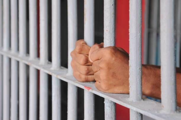 istock close up of prisoner hands in jail background. 2186489049
