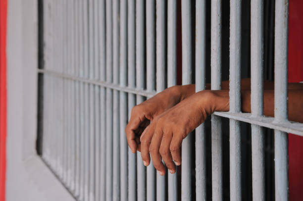 istock close up of prisoner hands in jail background. 2186489050