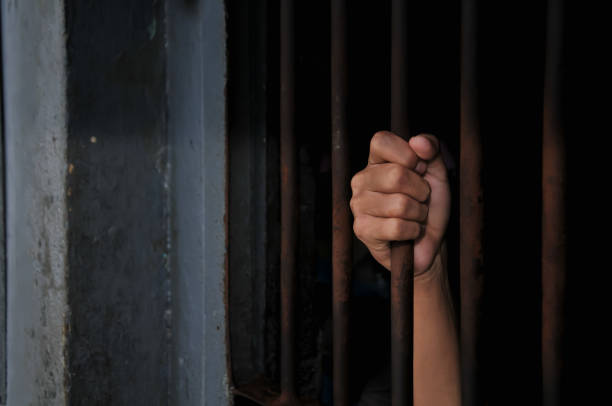 istock close up of prisoner hands in jail background. 2186489285