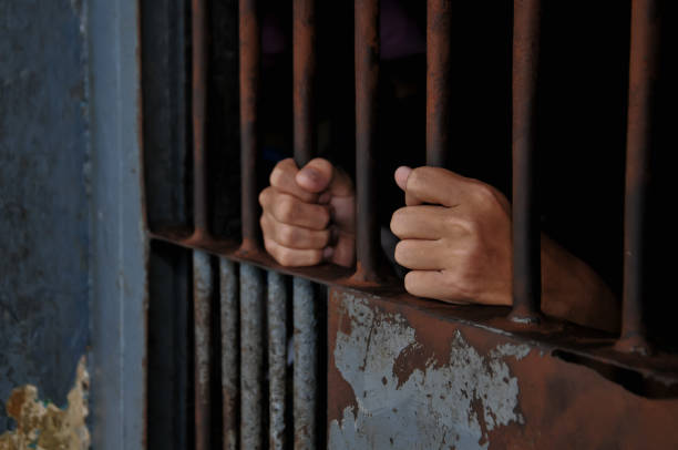 istock close up of prisoner hands in jail background. 2186489307