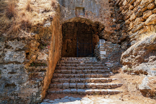 An ancient stone staircase leads to a gated archway at the historic Castle of Kalamata, showcasing medieval architecture and history.