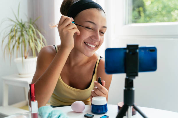 istock Young woman applying mascara with smile, live streaming 2186498476