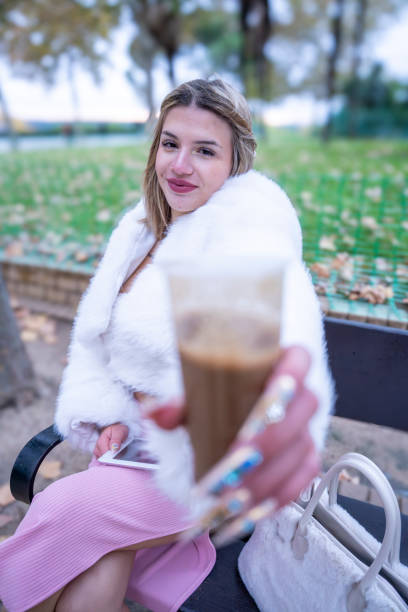 Woman in socks, boots and Christmas red hat sitting on a balcony in the mountains and drinking coffee at sunrise morning