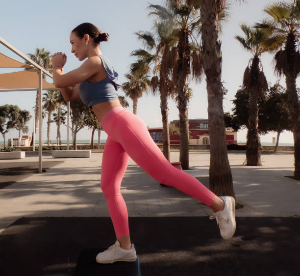 istock sporty girl doing leg exercise in a public park 2186501323