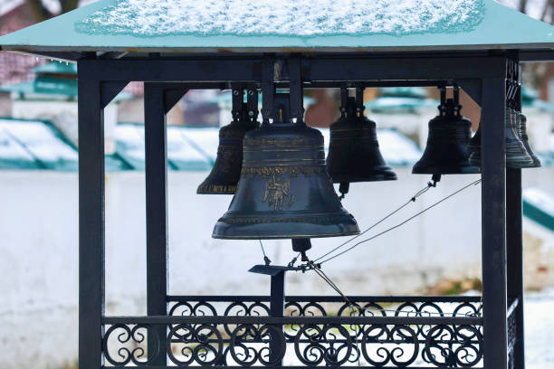 Church bells hang in a row, the bells are ringing. Ancient church tower big bell close up. Several church bells in the monastery.
