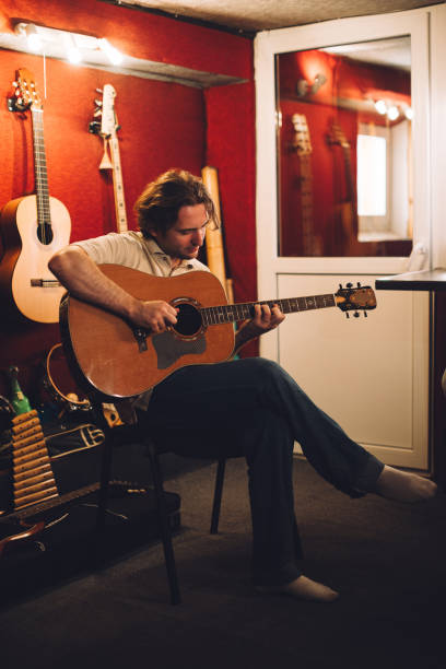 istock Guitarist strumming strings in a warm recording studio 2186509312
