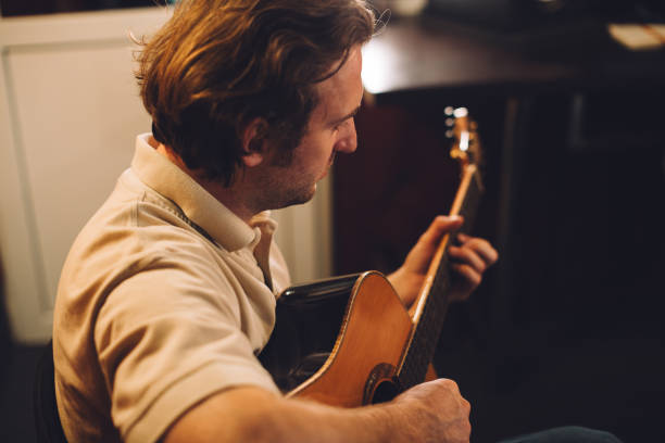 istock Close up. Young man playing acoustic guitar in recording studio. 2186509338