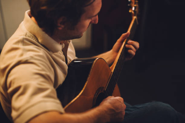 istock Close up. Young man playing acoustic guitar in recording studio. 2186509339