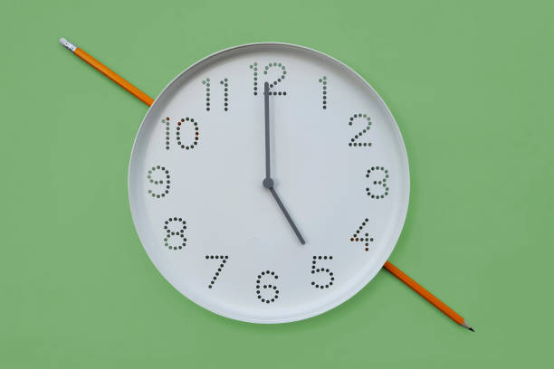 istock Clock and pencil. Round white wall clock shows 5 o'clock on plain green background copy space. Symbol of working hours, end of work in office or study at 17 oclock, deadline 2186510669