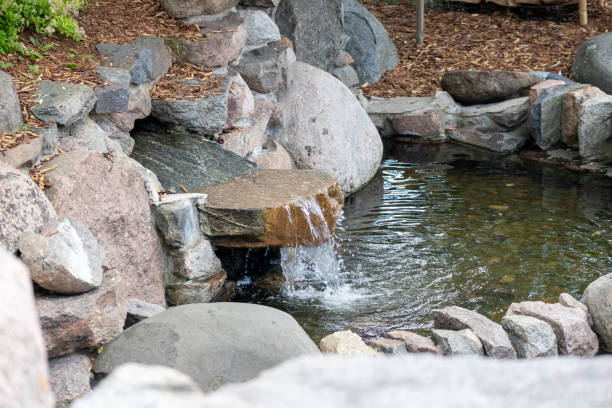 istock .A fountain on a stone wall flows into the water 2186513693