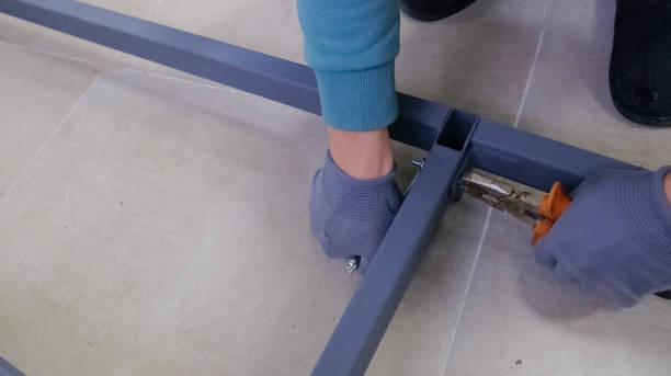 istock The process of assembling a metal structure. A man's hand in a work glove uses a tool to work with a bolted connection. The metal frame is painted gray and the action takes place on a tiled floor. 2186514632