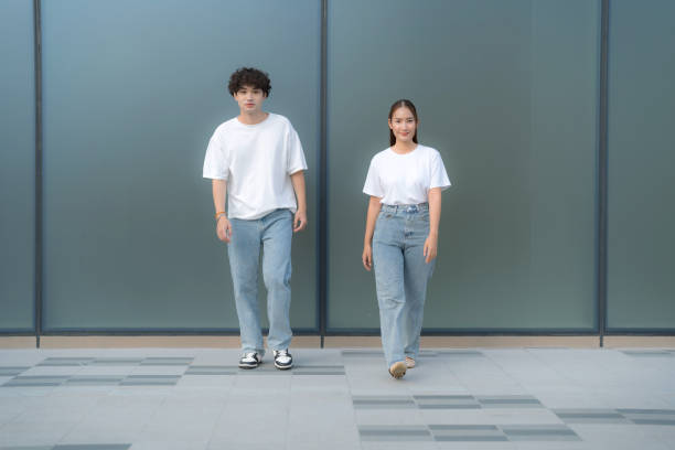 istock Young couple wearing white t-shirts and jeans posing against a wall 2186514830