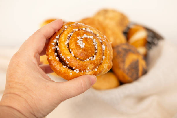 istock bun in female hand, Assorted blush-colored pastries, bread products, bakery, poppy seed rolls, indulgence and dietary discipline 2186516401