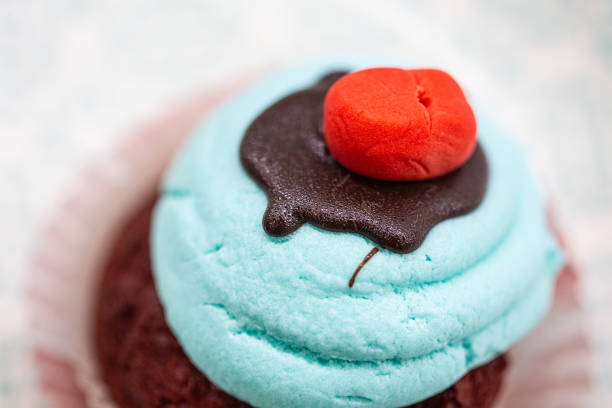 Blue velvet sugar muffin cupcake with red top on a white background