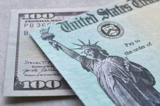 istock United States Government Treasury check with hundred dollar bill. 2186529275