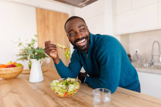 istock Happy man enjoying salad in bright kitchen with plants around 2186531813