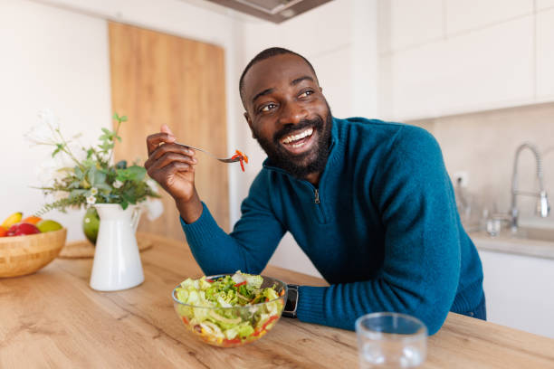 istock Cheerful man enjoying salad in kitchen with bright smile 2186531836