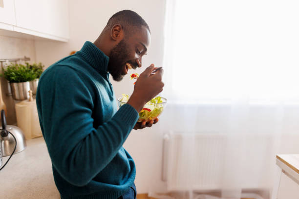 istock Joyful man savoring fresh salad at home, kitchen window open 2186531849