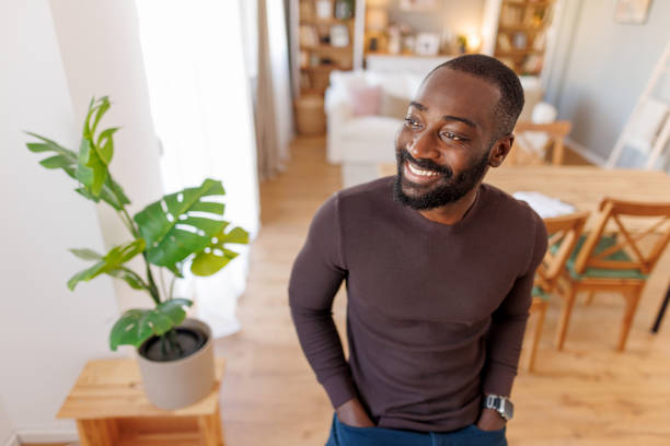 istock Bearded man stands smiling hands in pockets at home interior. 2186531934