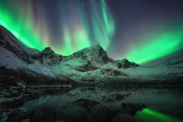 istock Mesmerizing green northern lights dance above snowy mountains, casting vibrant glow on tranquil lake, creating magical atmosphere in dark night 2186532189