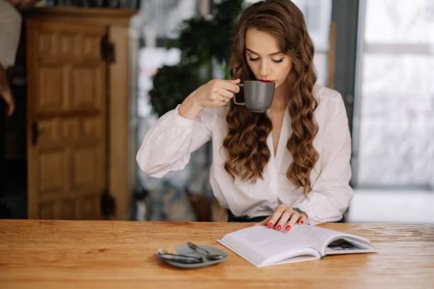 istock Young woman drinking coffee and reading book in cafe 2186537831