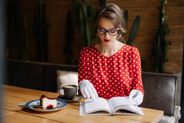 istock Young woman reading book and enjoying coffee break in cafe 2186538525